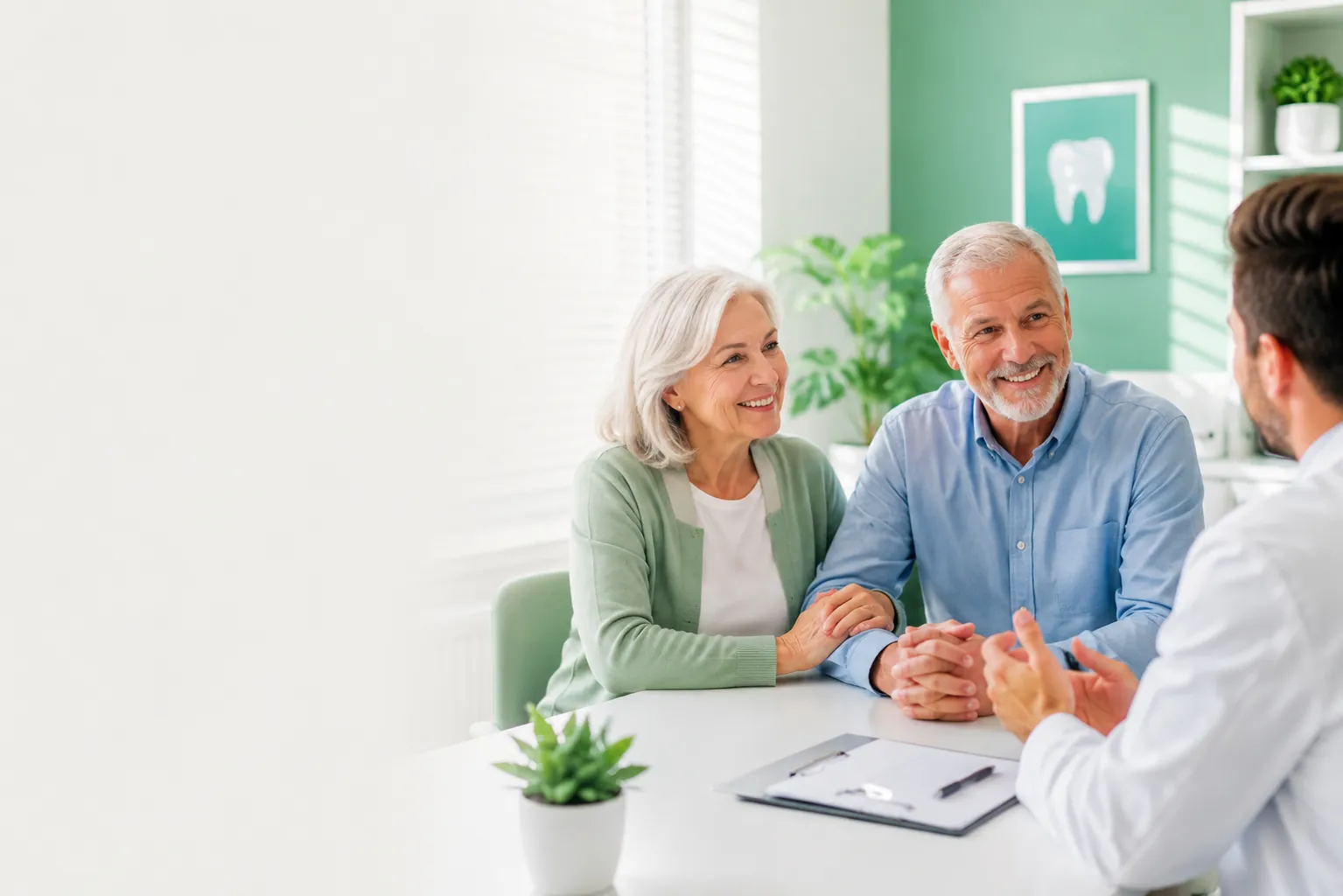 Older adult couple reviewing dental plan comparison information with a dentist during a consultation.